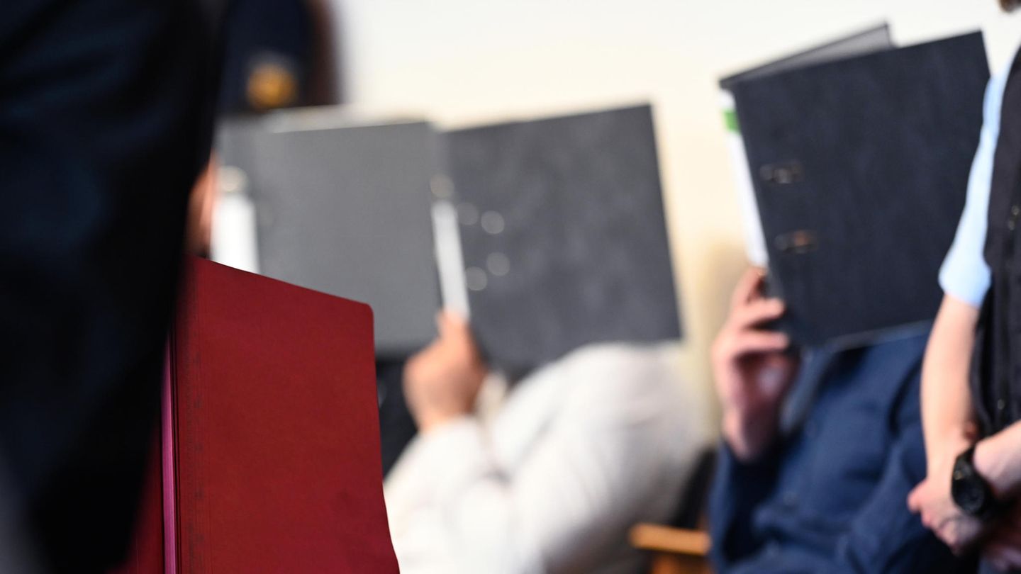 Die Angeklagten sitzen vor dem Prozessbeginn im Gerichtssaal im Landgericht