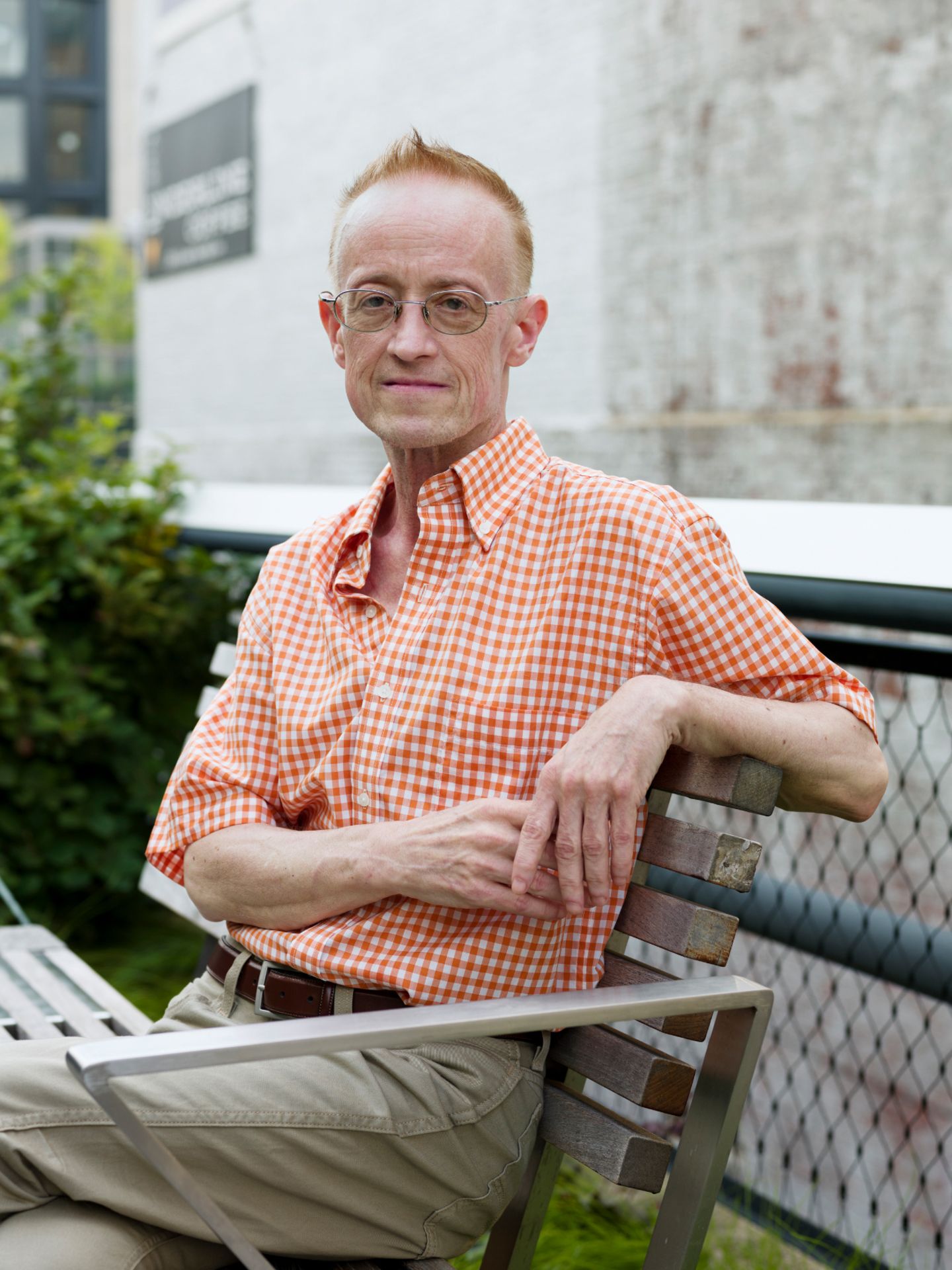 Ein älterer Mann mit Brille sitzt auf einer Gartenbank