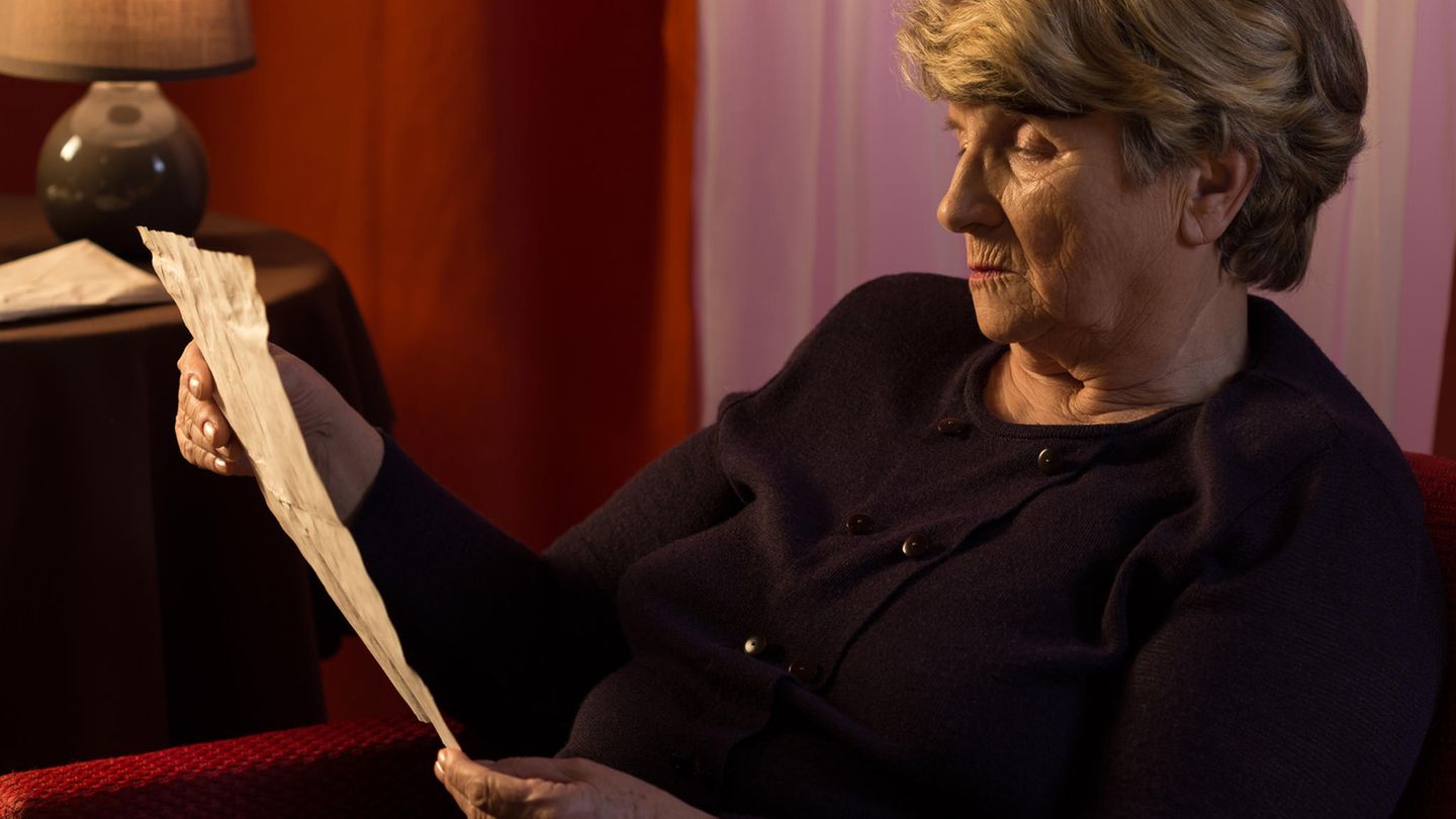 Eine Seniorin hält einen Brief in den Händen