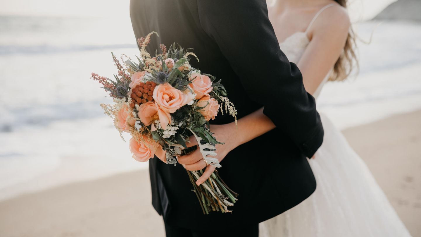 Eine Frau und ein Mann in Hochzeitskleidung umarmen sich innig