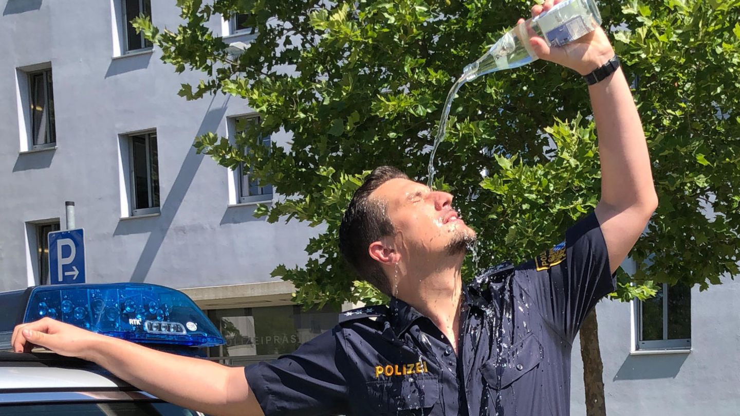 Ein Polizist gießt sich eine Flasche Wasser über das Gesicht