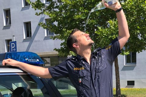 Ein Polizist gießt sich eine Flasche Wasser über das Gesicht