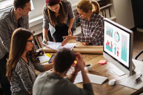 Fünf junge Menschen sitzen an einem Tisch und diskutieren über einen Plan