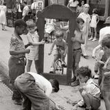 Kinder spielen und Erwachsene plaudern auf dem Bürgersteig