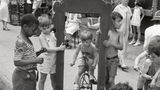 Kinder spielen und Erwachsene plaudern auf dem Bürgersteig