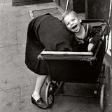 Ein Junge strahlt aus dem Kinderwagen heraus