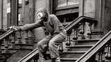 Ein maskierter Junge steht auf der Treppe eines Hauseingangs