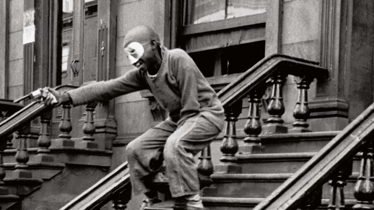 Ein maskierter Junge steht auf der Treppe eines Hauseingangs