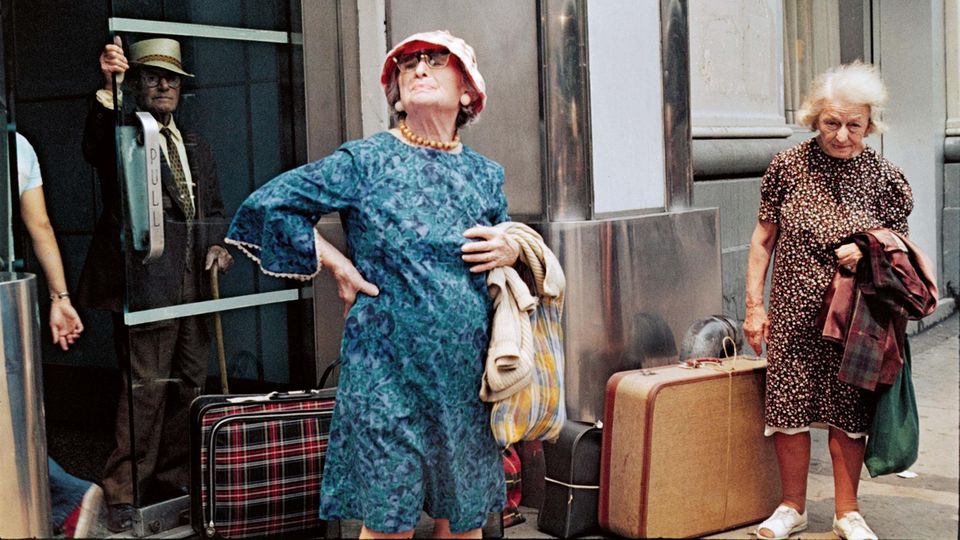 Zwei alte Damen mit Koffern am Straßenrand