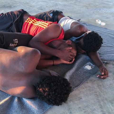 Die Aufnahme zeigt drei gerettete Bootsflüchtlinge, die verzweifelt in einem Migrantenlager in Libyen gestrandet sind.