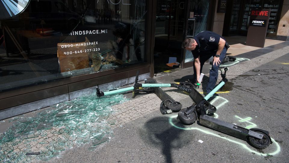 Ein Polizist markiert nach einem Verkehrsunfall in der Mohrenstraße E-Scooter