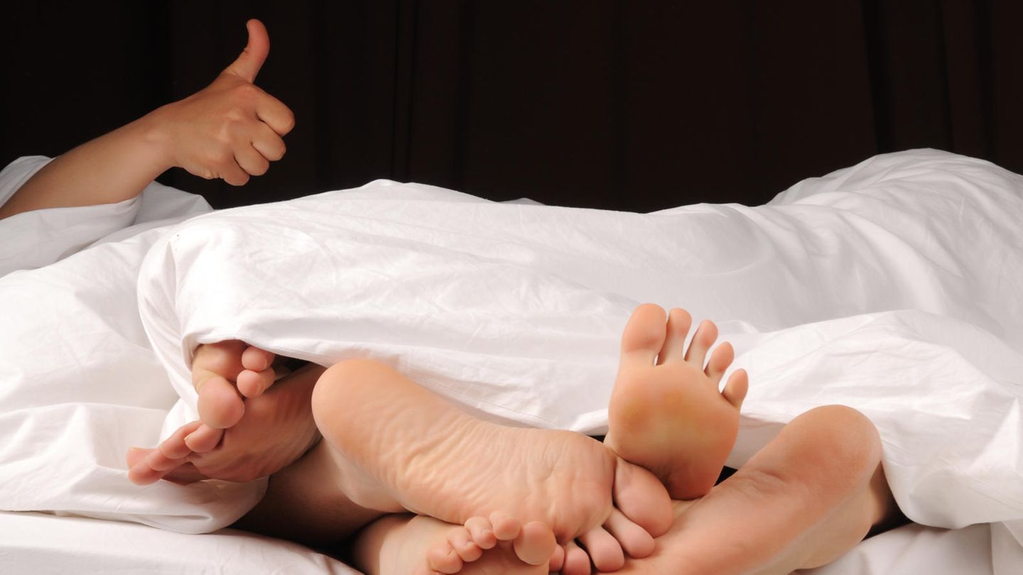 Drei paar Füße in einem Doppelbett