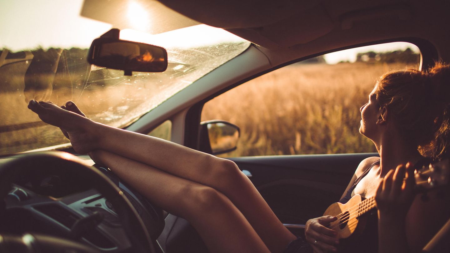 Frau sitzt bei Sonnenuntergang im Auto