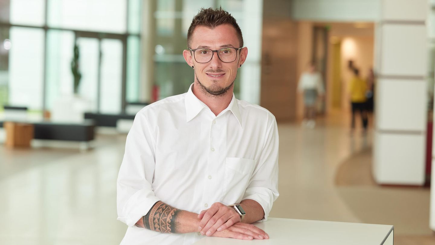 HIV: Jörg Beißel steht vor einem weißen Tisch und lächelt in die Kamera