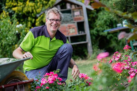René Wadas sitzt in einem Garten vor Blumen