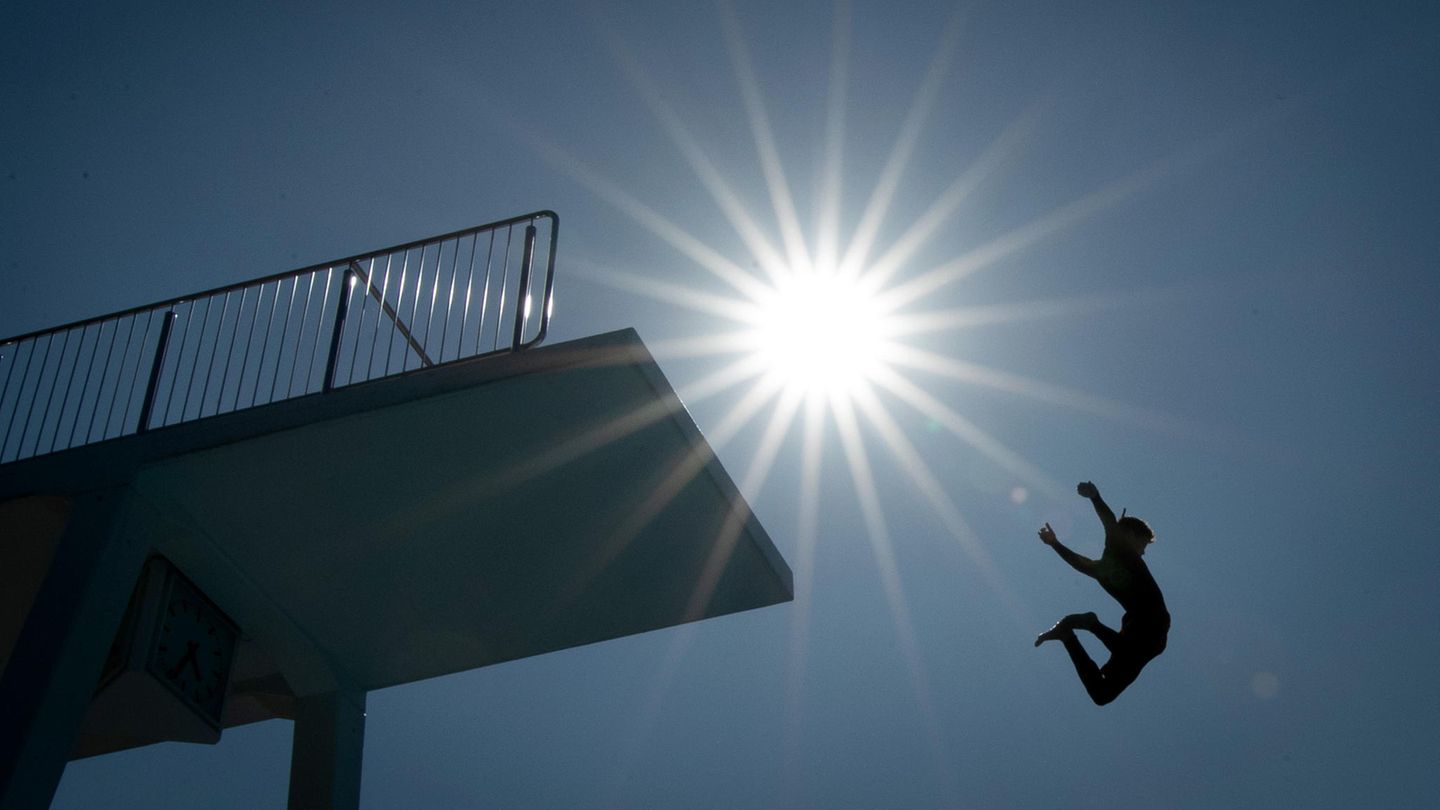 Ein Badegast springt vom 10-Meter-Turm in einem Freibad