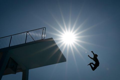 Ein Badegast springt vom 10-Meter-Turm in einem Freibad