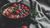 Beeren: Eine Schale mit Porridge und Himbeeren steht auf einem Tisch