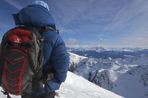 Frau in dicker Daunenjacke mit Rucksack auf dem Schrotthorn, dahinter Dolomiten mit Langkofel