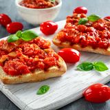 Kirschtomatenrelish aus dem Ofen  Für 600 ml  Zutaten: 125 g Perlzwiebeln, 1 Knoblauchzehe, 1/2–1 rote Peperoni, 250 g sehr kleine Kirsch- oder Datteltomaten, 1 kleine feste Zucchini (ca. 100 g), 100 g kleine kernlose Weintrauben, 1 EL Olivenöl, ½ EL Zucker, Meersalz, 40 ml Rotweinessig, 100 ml Apfelsaft, 1 Lorbeerblatt, 15 cm Rosmarinzweig, 2–3 Thymianzweige  Zubereitung: Zwiebeln und Knoblauch abziehen. Peperoni entkernen. Knoblauch und Peperoni sehr fein schneiden. Tomatenschalen leicht einritzen. Zucchini fein würfeln. Trauben von den Rispen zupfen. Den Backofen auf 180 Grad Ober-/Unterhitze vorheizen. Zwiebeln in einer ofenfesten Pfanne bei milder Hitze in Öl unter Wenden langsam goldbraun anbraten. Zucker darüberstreuen und karamellisieren. Zucchini, Peperoni und 1 TL Salz unterrühren. Mit Essig und Saft ablöschen. Lorbeer, Kräuter, Tomaten und Weintrauben dazugeben, aufkochen und in der Pfanne auf der zweiten Einschub-Ebene von unten in den Ofen schieben. Nach 15 Minuten wenden und weitere 15 Minuten garen. Abkühlen lassen. Mit einer Pinzette die Häutchen von den Tomaten zupfen.