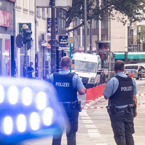 Polizeibeamte und ein Fahrzeug mit Blaulicht stehen vor einer Filiale der Frankfurter Sparkasse an der Düsseldorfer Straße. Auf die Filiale wurde ein Raubüberfall verübt.