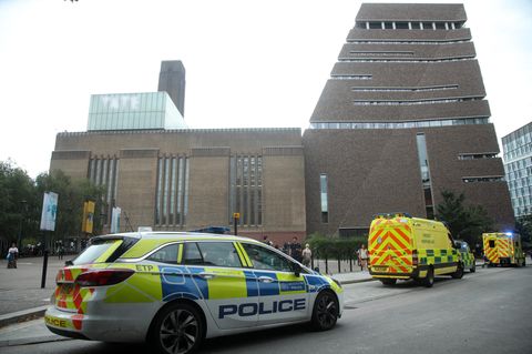 Vor einem hohen Backsteingebäude in London stehen zwei Polizeiwagen und ein Krankenwagen mit Blaulicht