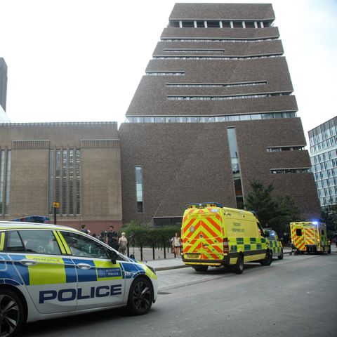 Vor einem hohen Backsteingebäude in London stehen zwei Polizeiwagen und ein Krankenwagen mit Blaulicht