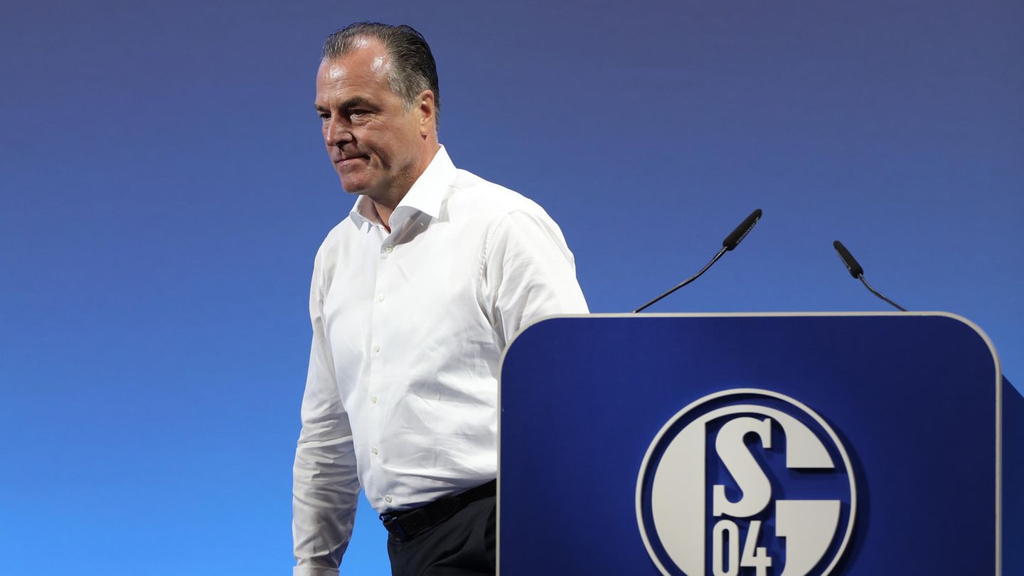 Clemens Tönnies - in weißem Hemd und schwarzer Hose - geht vom Rednerpult mit blau-weißem "Schalke 04"-Logo weg