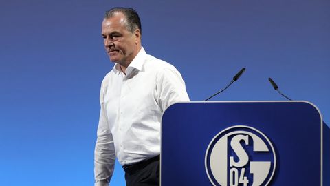 Clemens Tönnies - in weißem Hemd und schwarzer Hose - geht vom Rednerpult mit blau-weißem "Schalke 04"-Logo weg