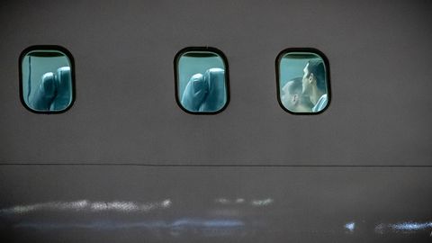 Blick von außen auf ein Flugzeug, hinter den Scheiben sind Menschen zu sehen