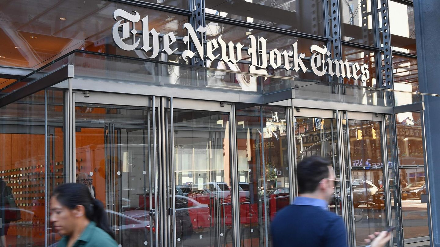 Vor einem gläsernen Eingang unter einem "The New York Times" Schriftzug laufen Menschen mit Smartphone in der Hand vorbei