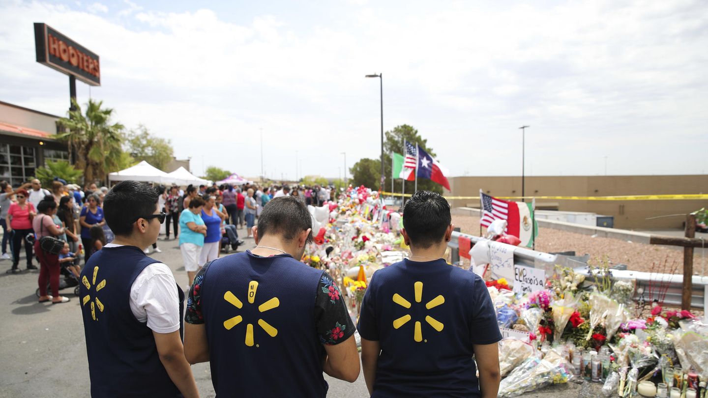 Menschen stehen vor Blumen nach Massenschiesserei