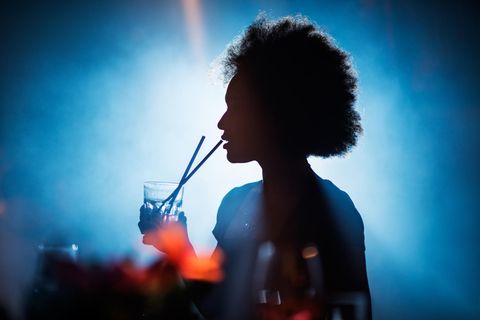 Gefahr durch K.-o.- Tropfen: Eine Frau feiert und trinkt einen Cocktail im Club