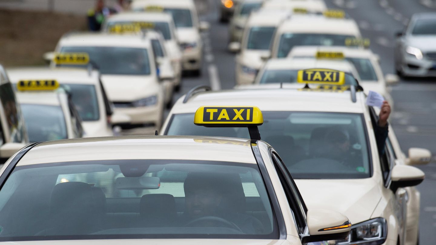 Taxen, die hintereinander und nebeneinander fahrend zwei Spuren einer Straße belegen.