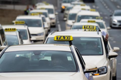 Taxen, die hintereinander und nebeneinander fahrend zwei Spuren einer Straße belegen.