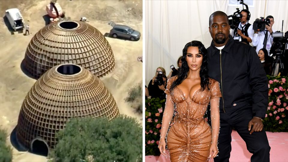 Kanye West und seine Frau Kim Kardashian posieren bei einem Event für Fotografen. Links stehen halbkugelförmige Häuser