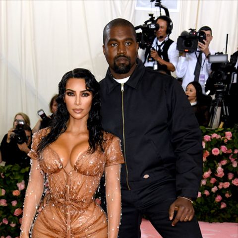 Kanye West und seine Frau Kim Kardashian posieren bei einem Event für Fotografen. Links stehen halbkugelförmige Häuser