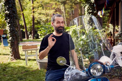 Mann sitzt freudig auf einem Motorroller