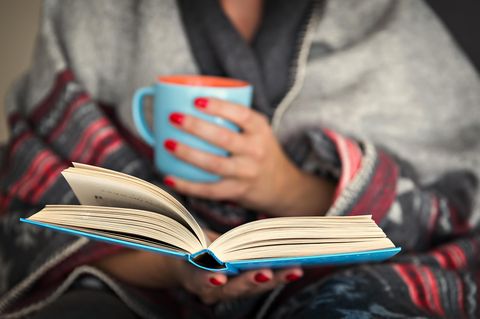 Frau mit Buch und Teebecher