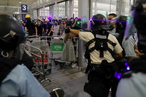 China, Hongkong: Polizisten in Schutzausrüstung stehen gegenüber Demonstranten am Haupteingang des Hongkonger Flughafen