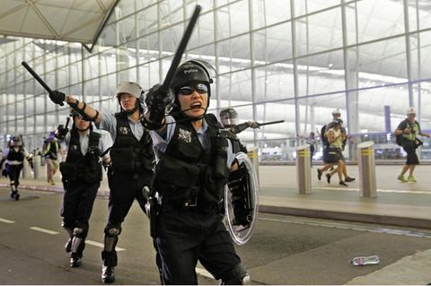 China, Hongkong: Polizisten mit Schlagstöcken schreien Demonstranten im Hongkonger Flughafen an