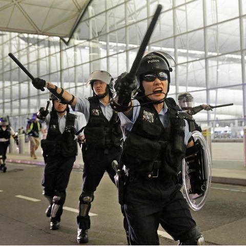 China, Hongkong: Polizisten mit Schlagstöcken schreien Demonstranten im Hongkonger Flughafen an