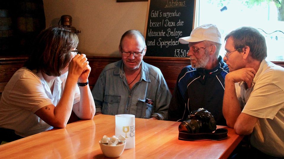 Melanie, Siegfried, Dieter und Frank (v.l.n.r.) sitzen gemeinsam in der Kneipe und unterhalten sich Melanie, Siegfried, Dieter und Frank (v.l.n.r.) sitzen gemeinsam in der Kneipe und unterhalten sich