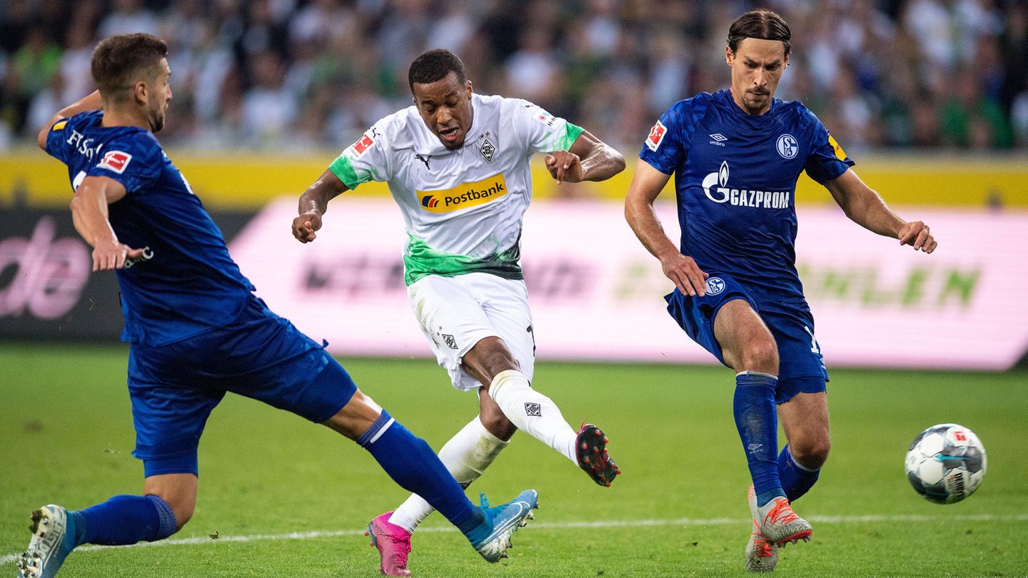 Gladbachs Alassane Plea (m.) schießt aufs Tor. Links läuft Schalkes Matija Nastasic und rechts Benjamin Stambouli
