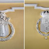 Hoch oben an den Stirnseiten der Lobby prangen die Wappen beider Länder: das Hoheitszeichen der République française, der dritten französischen Republik (links), und das Wappen Spaniens mit Königskrone und Bourbon im Herzschild (rechts).