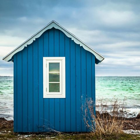 Blaues Badehäuschen mit Meer im Hintergrund