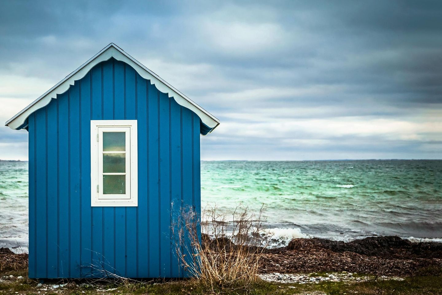 Blaues Badehäuschen mit Meer im Hintergrund
