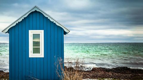 Blaues Badehäuschen mit Meer im Hintergrund
