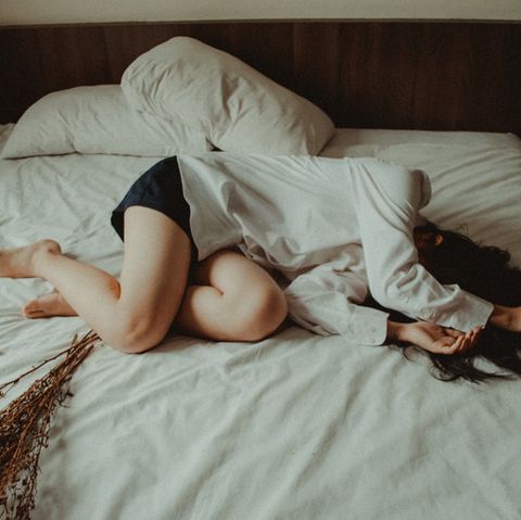 Frau liegt traurig im Bett