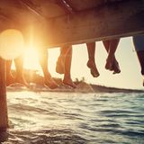 Menschen sitzen auf Steg am Wasser